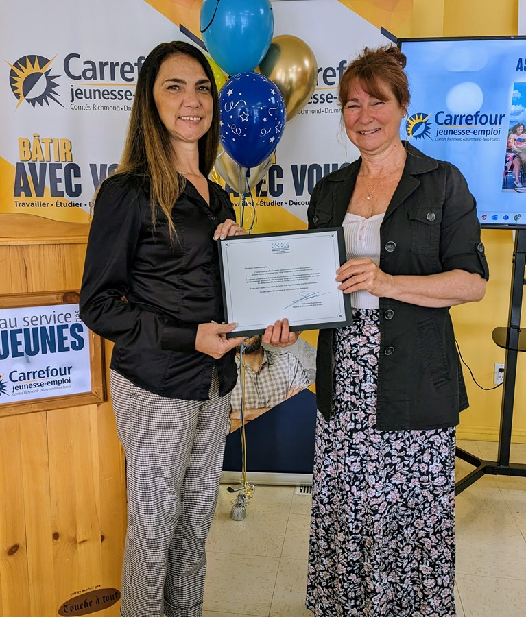 Madame Stéphanie Auger, représentante de M. Sébastien Schneeberger, député de Drummond–Bois-Francs remettant un certificat de l’Assemblée nationale du Québec à Sylvie Bibeau, directrice du Carrefour jeunesse-emploi.